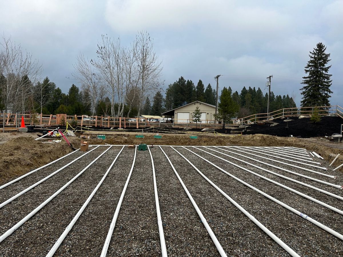 Engineered pressurized septic drainfield with parallel PVC laterals and inspection ports installed by Premier Land Service on a commercial property in Sagle, Idaho.