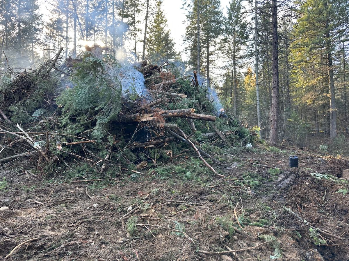Slash burn pile actively smoking, crew working it down — Premier Land Service slash removal, North Idaho