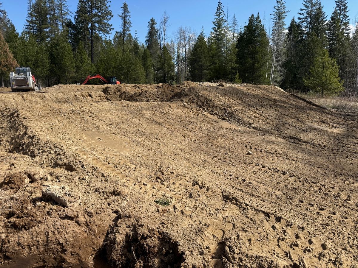 Custom kids' pit bike track with shaped berms and rollers cut into a Sagle, Idaho property by Premier Land Service using skid steer and mini excavator.