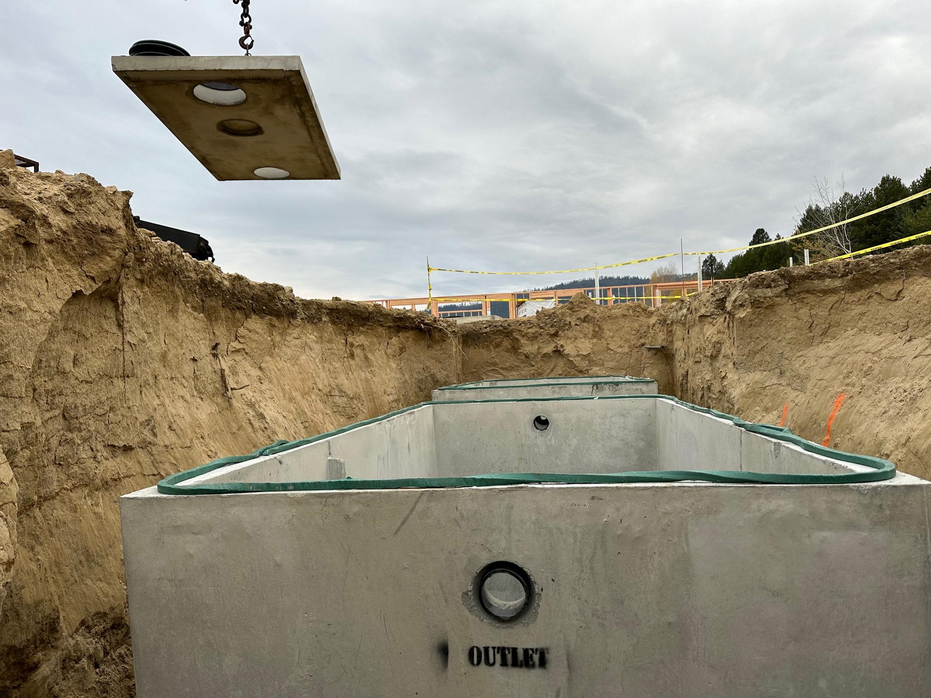 Close up of concrete septic tank outlet chamber being lowered by crane
