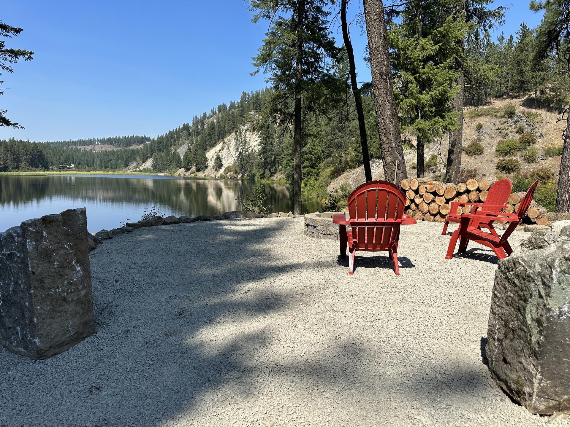 Completed lake terrace with red Adirondacks and fire pit