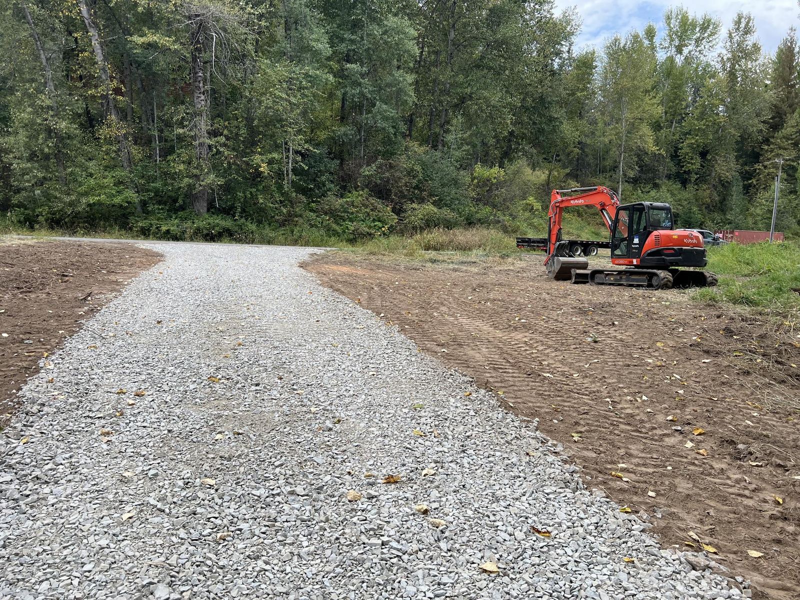 Pristine white gravel driveway winding through green forest Premier Land Service
