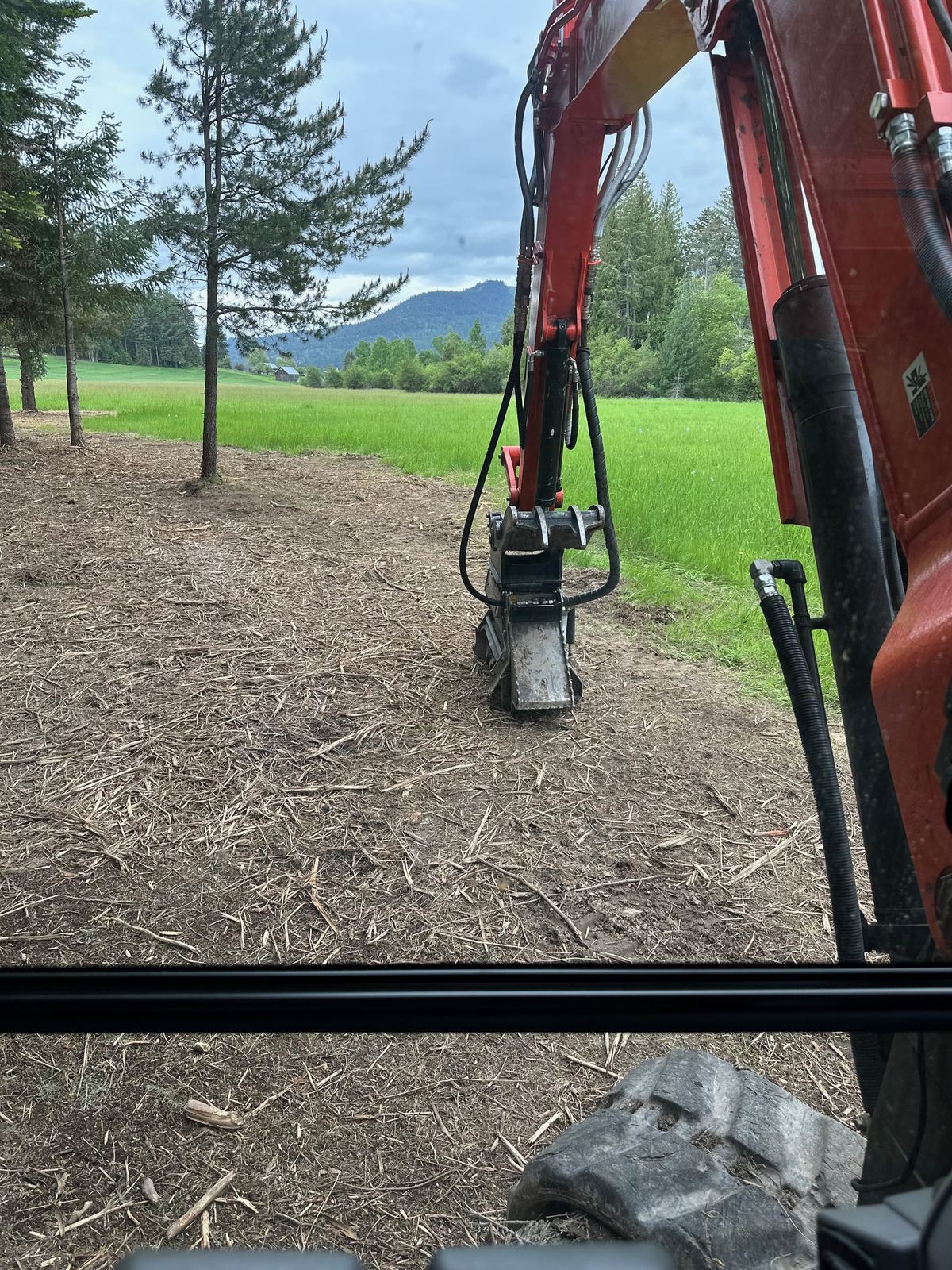 Kubota excavator with forestry mulcher head on a North Idaho property — Premier Land Service forestry mulching in progress
