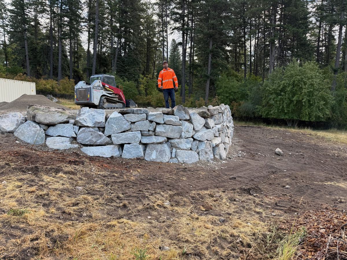 Granite boulder retaining wall built by the Premier Land Service crew with a compact track loader