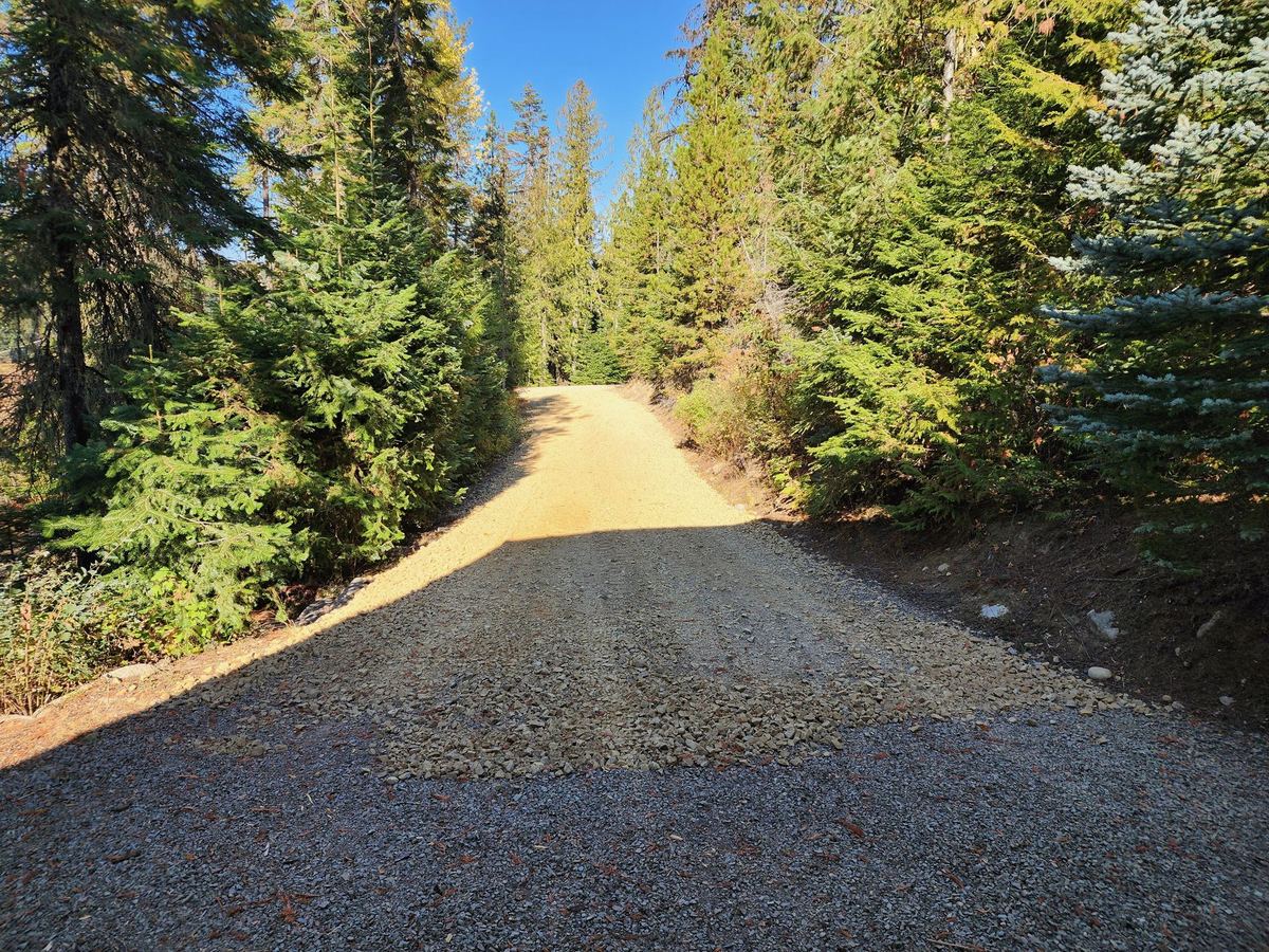 Finished gravel private driveway through North Idaho conifers — Premier Land Service road build