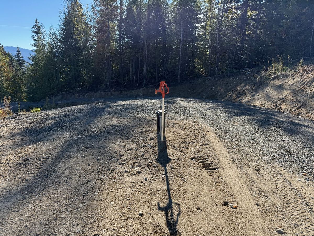 Finished graded gravel pad with yard hydrant and Selkirk mountain view — Premier Land Service grading