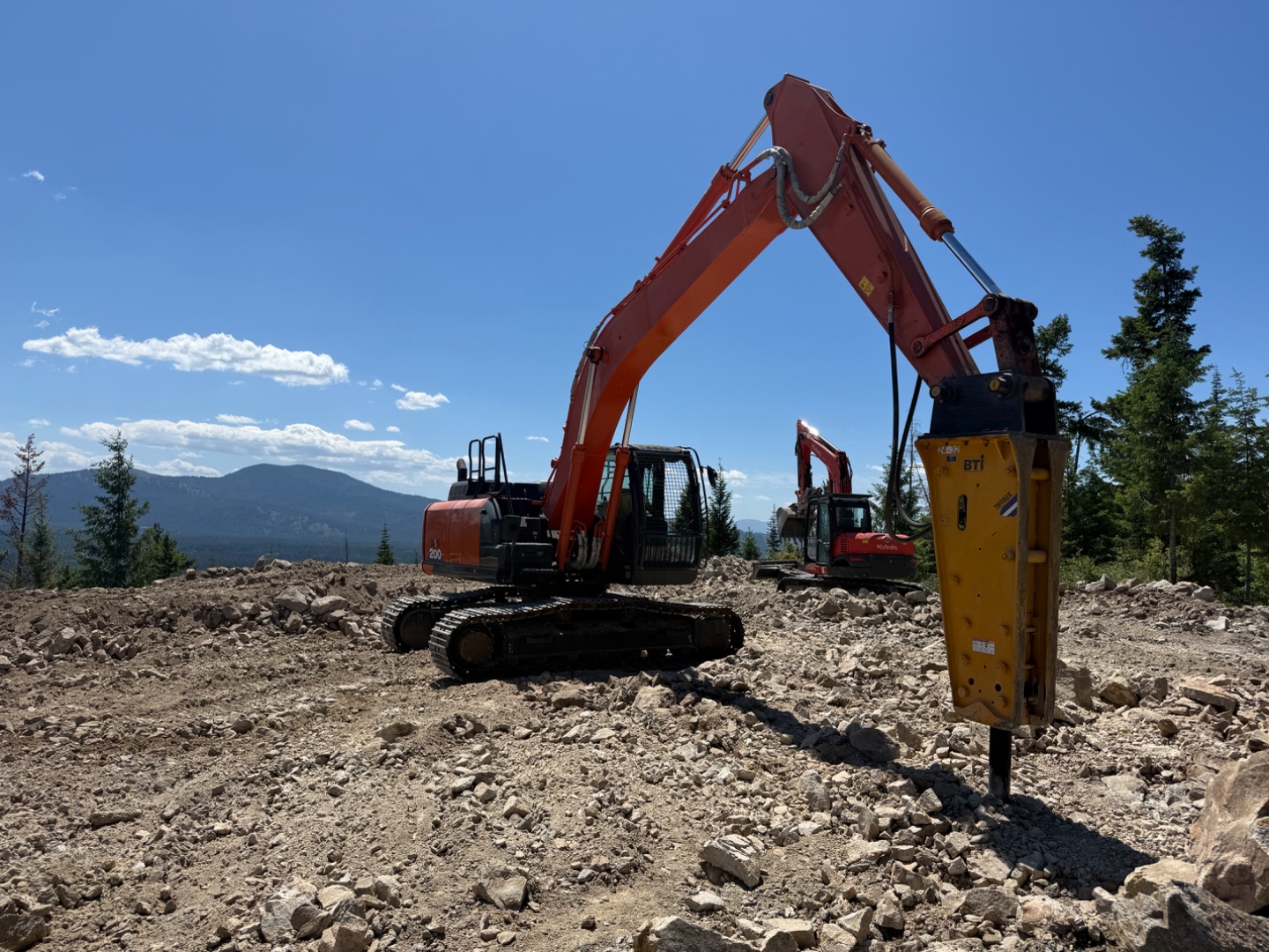 Premier Land Service Hitachi Zaxis 200 excavator on a Sagle site with sweeping North Idaho mountain views