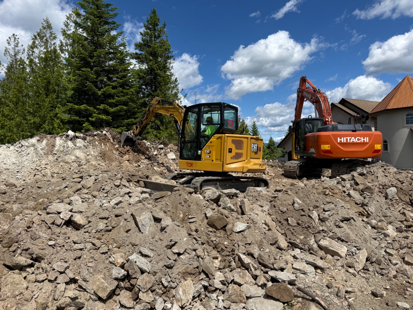Two Premier Land Service excavators preparing a residential house pad in Sandpoint, Bonner County
